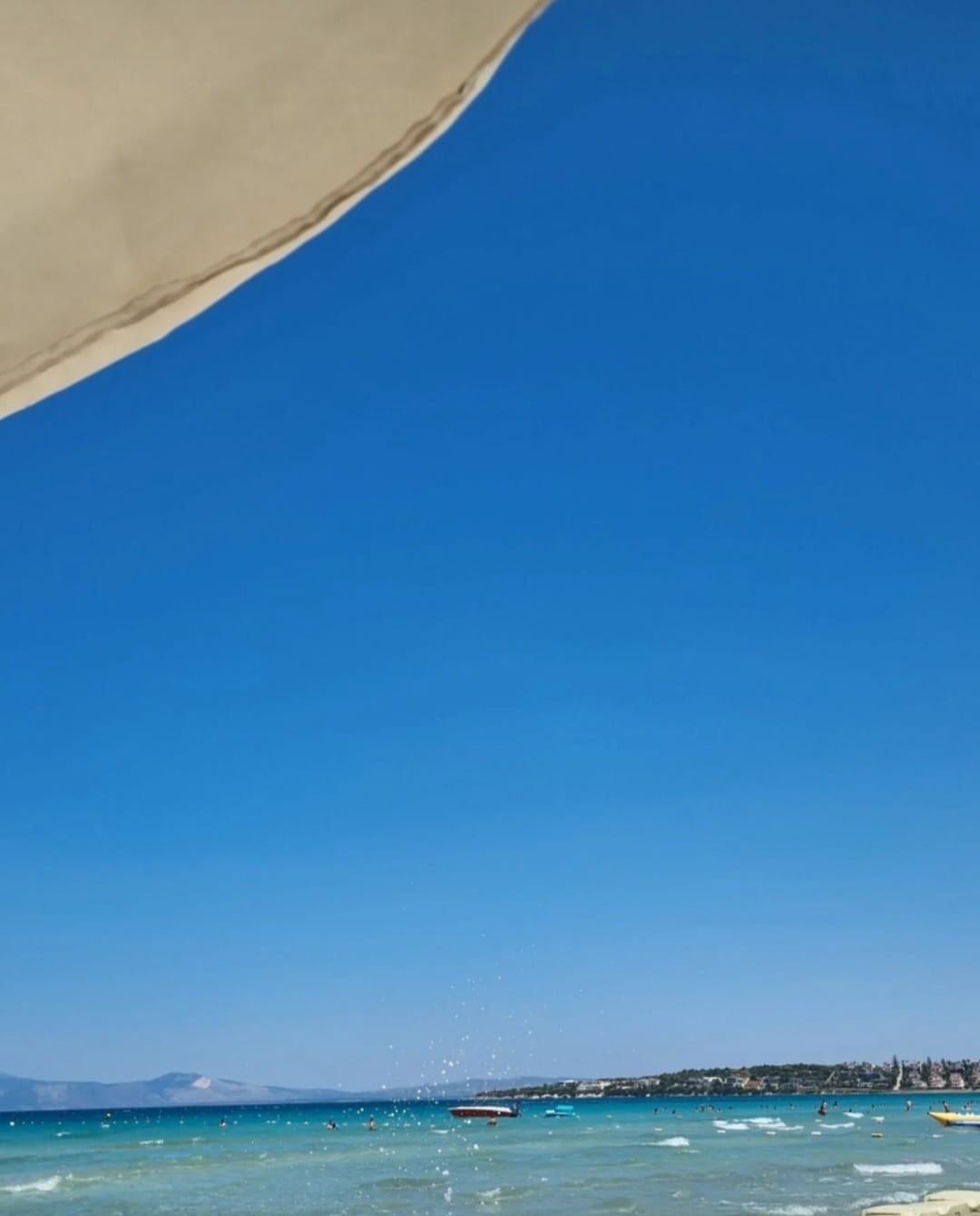 Şemsiye gölgesinden açık mavi deniz ve gökyüzü manzarası