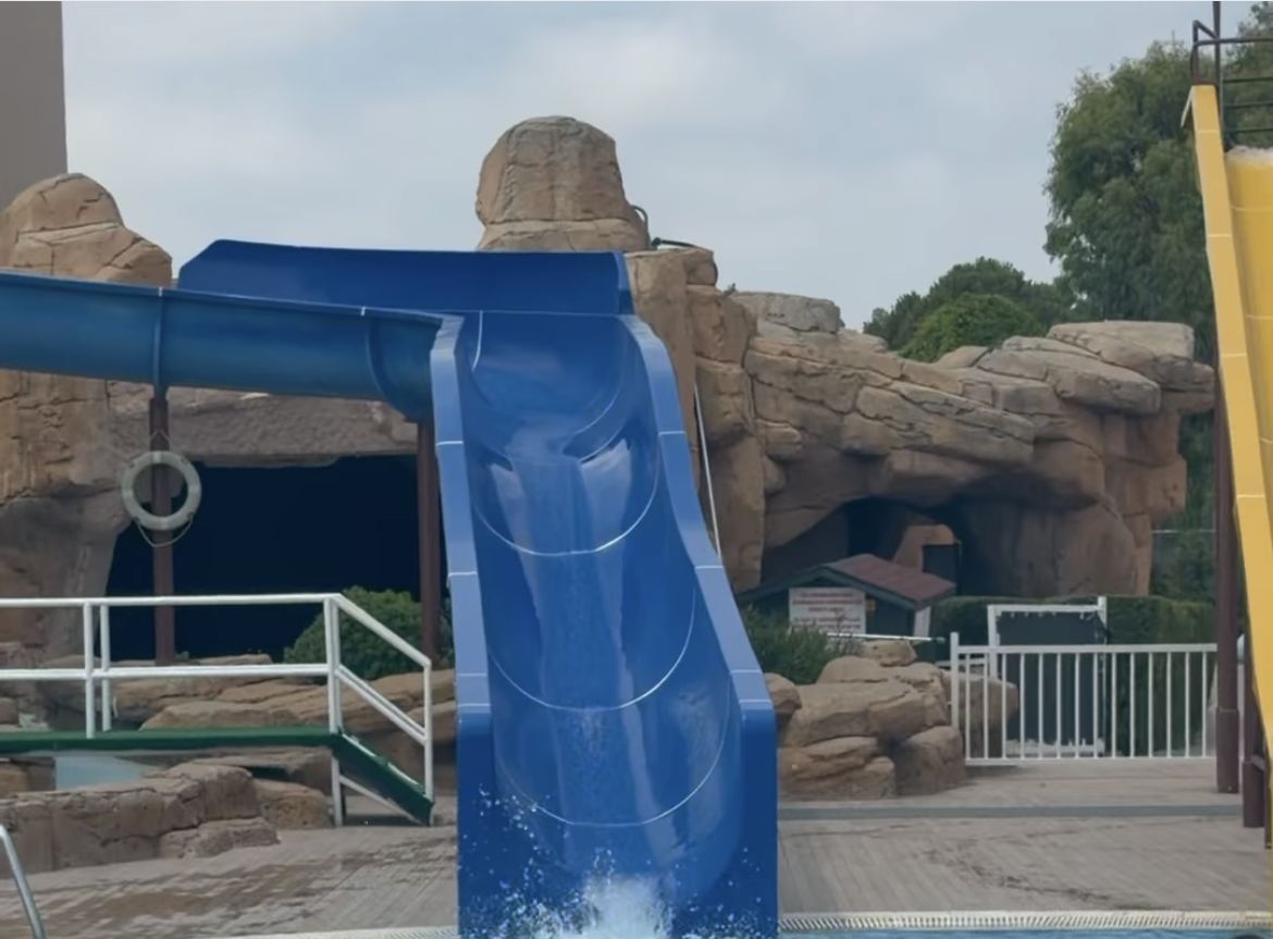 Kayalık dekorlu aquaparkta mavi kaydırak ve su sıçraması
