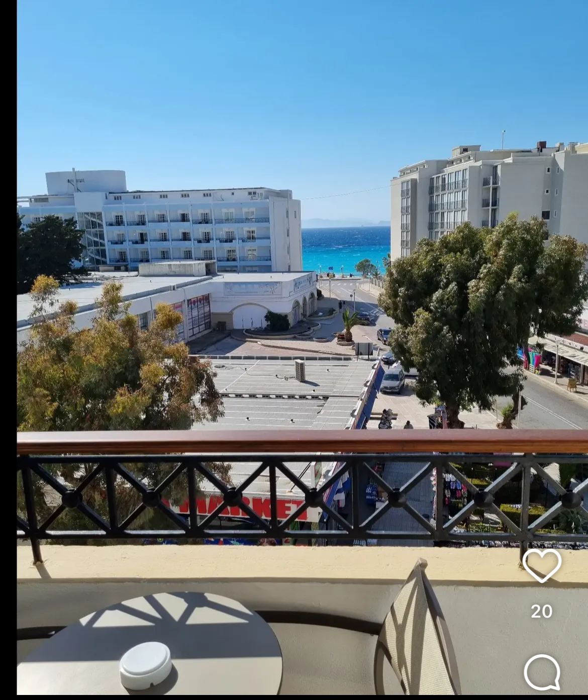Balkon korkuluğunun ardında cadde, binalar ve turkuaz deniz